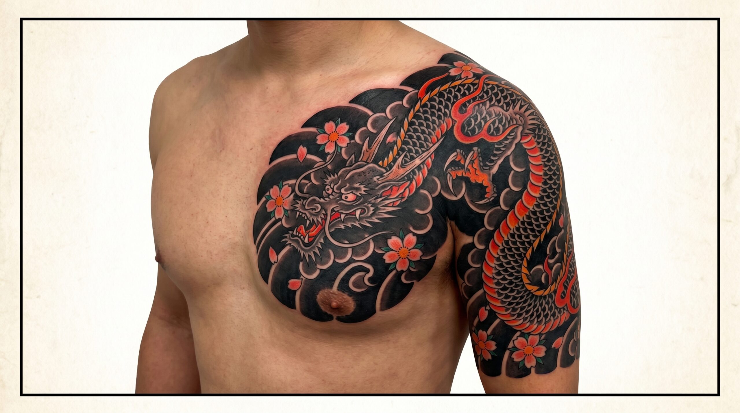 Classico tatuaggio giapponese Irezumi sul pettorale e sulla spalla. Raffigura un feroce drago Ryu che si muove tra oscure nuvole “Gakubori” e fiori di ciliegio. Profonda saturazione di inchiostro nero con vivaci accenti rossi, che seguono naturalmente la forma del muscolo pettorale.
