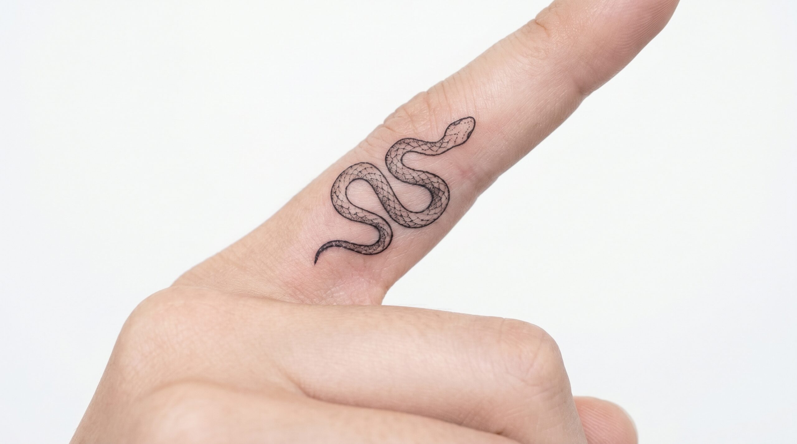 *Tatuaggio fine-line in inchiostro nero di un piccolo serpente avvolto realisticamente attorno a un dito umano, con squame dettagliate e micro-sfumature dotwork che creano un elegante senso di movimento, design pulito e minimalista.*
